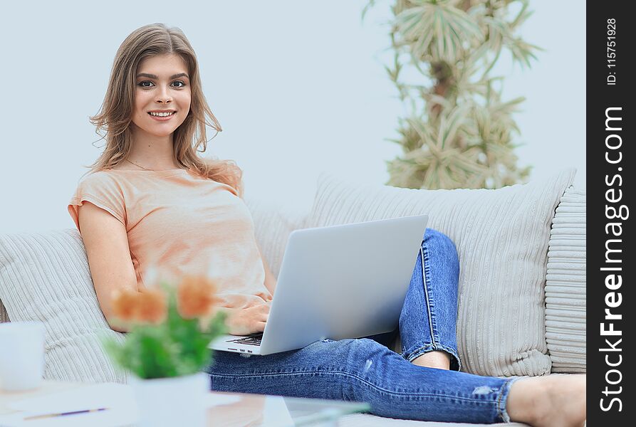 Beautiful girl with a laptop sitting on the couch.