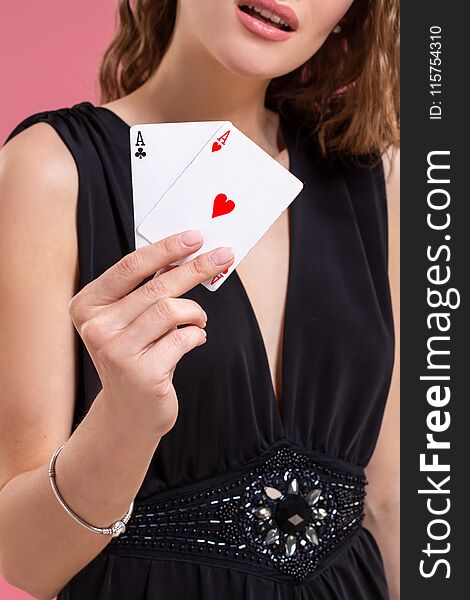 Beautiful caucasian woman in black dress with poker cards gambling in casino. Studio shot on a pink background. Beautiful caucasian woman in black dress with poker cards gambling in casino. Studio shot on a pink background