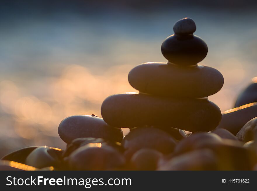 folded pyramid Zen pebble stones on the sea beach at sunset. folded pyramid Zen pebble stones on the sea beach at sunset