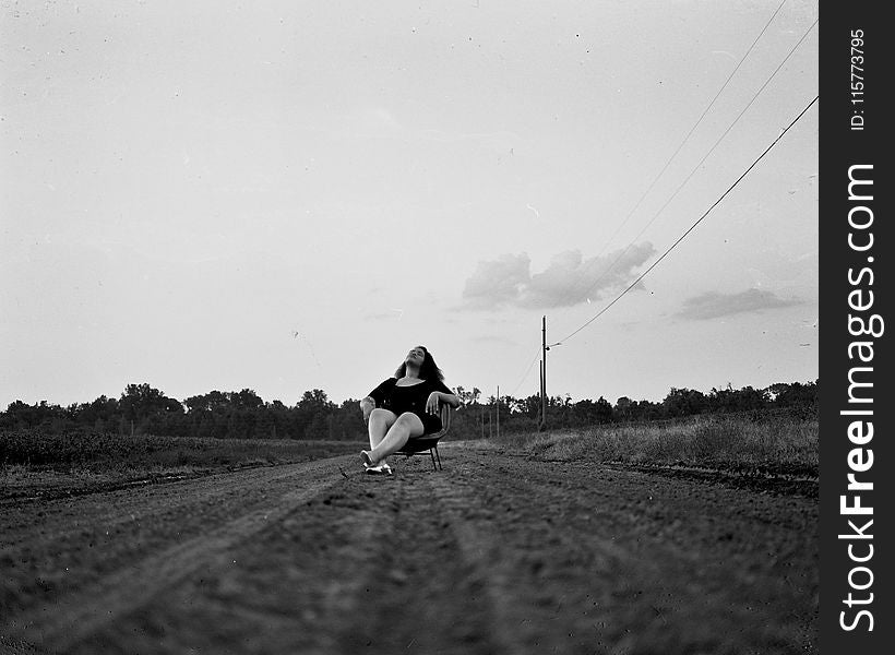 Grayscale Photography of Woman Sits on Chair on Pathway