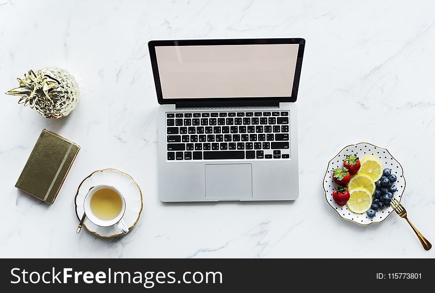 Macbook Pro Beside White Ceramic Mug And Saucer