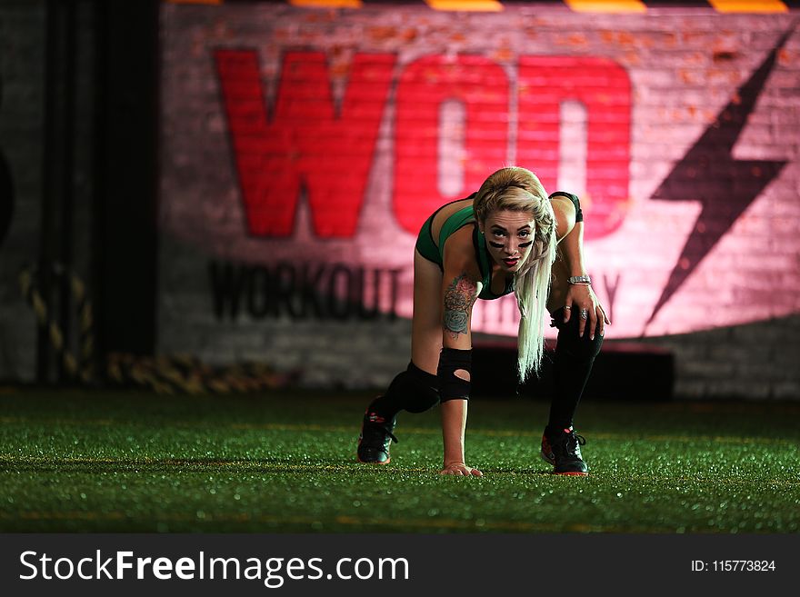 Photo Of Woman Wearing Green Top And Black Shorts Touching Grass