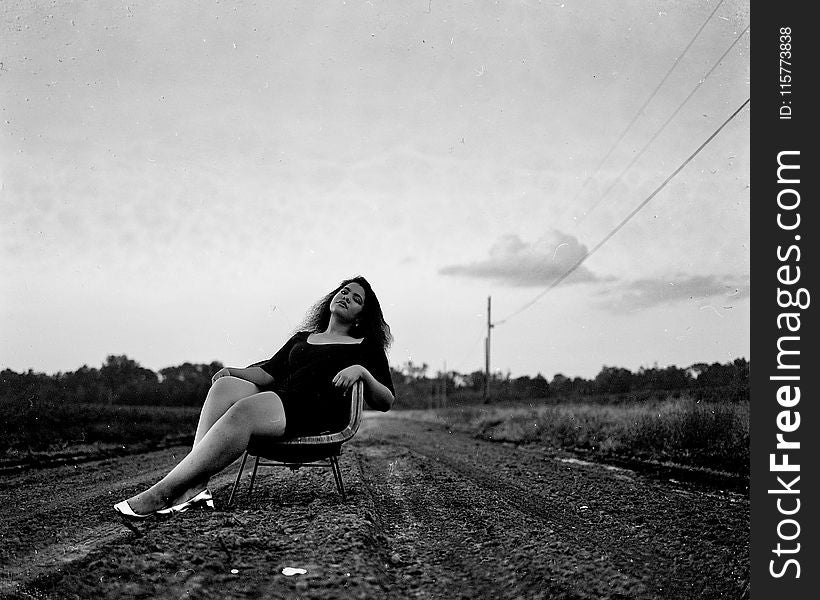 Black and White Photography of Woman on Chair on Road