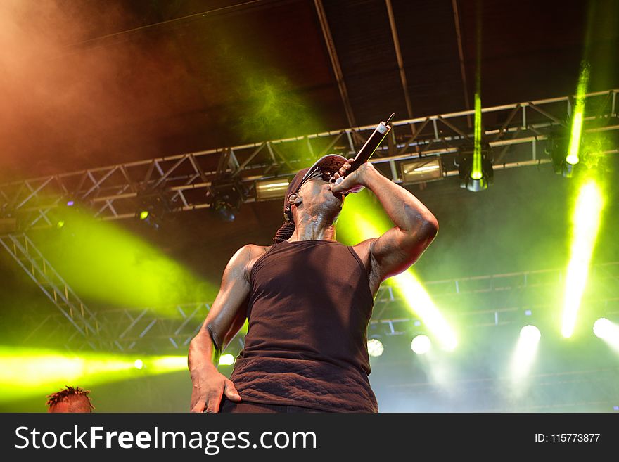 Man Wearing Black Tank Top Using Microphone on a Concert