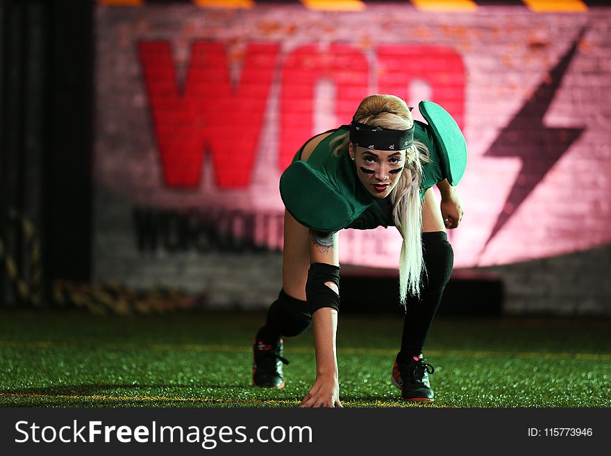 Woman In Green Shirt Crouching On Green Grass Lawn