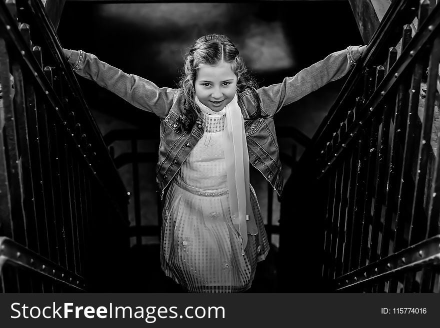 Grayscale Photo of Girl Standing on Stairs Holding Hand Rails