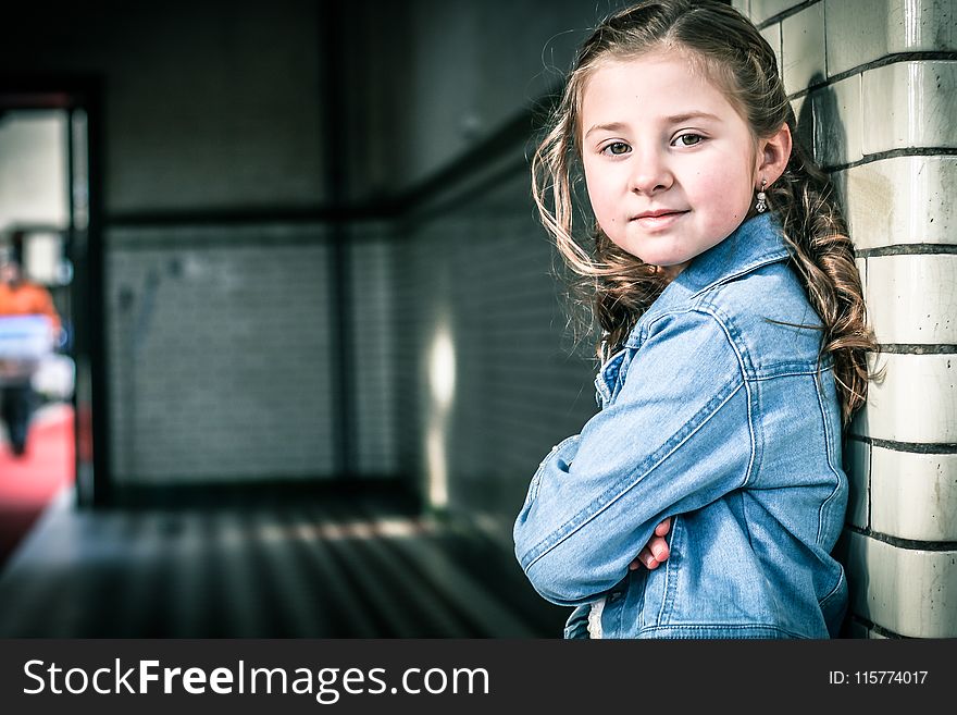 Girl in Blue Denim Jacket Leaning on Gray Wall