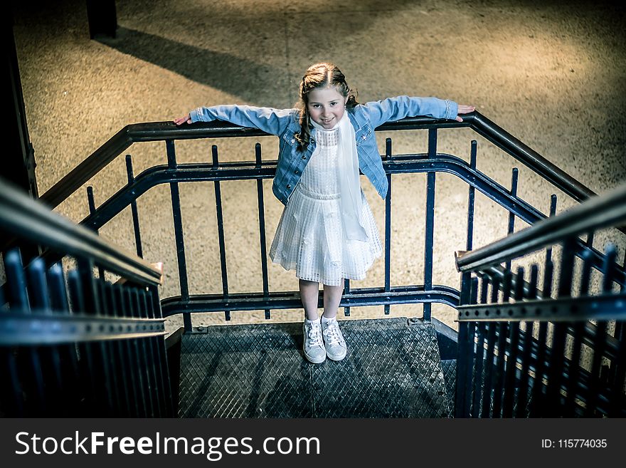Girl Wearing Blue Jacket and White Dress Standing on Railings during Night Time