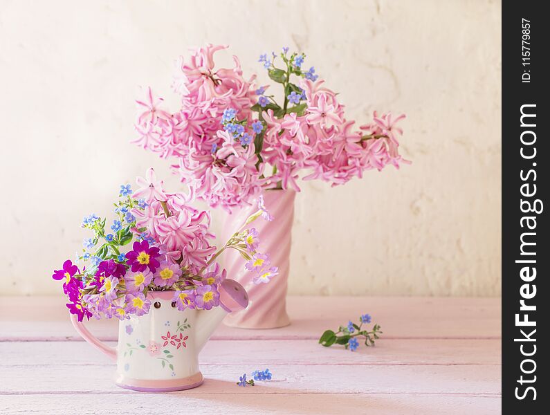 The spring flowers in vases on wooden table