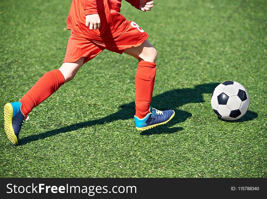 Child soccer player and ball on the football field