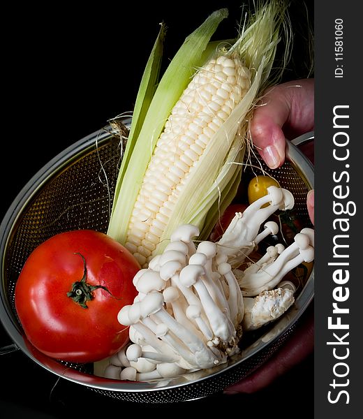 Mix of vegetables on black in  colander