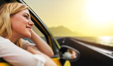 Travel Or Vacation. Beautiful Blond Girl In Car On The Road To The Sea At Sunset. Royalty Free Stock Photography