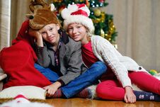 Smiling Teenage Girl And Boy Sitting On The Floor With A Christmas Tree In Background. Stock Image Smiling Teenage Girl And Boy Sitting On The Floor With A Christmas Tree In Background. Stock Image