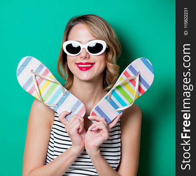 Young woman with flip flops shoes on green background