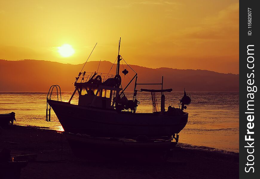 Sunset over fishing boat in the Strait of Messina, Italy