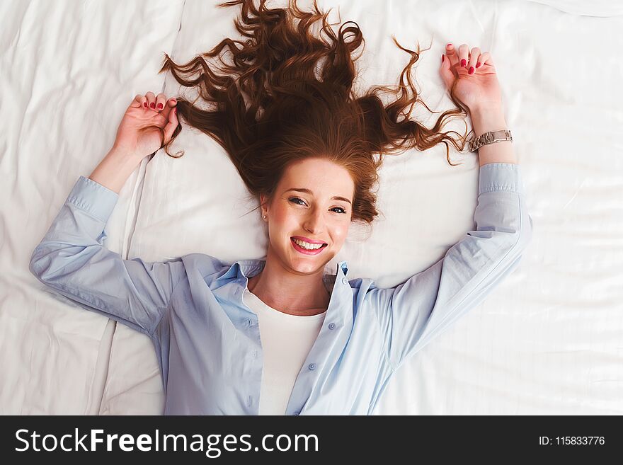 Beautiful smiling young red hair woman laying in bed on her back