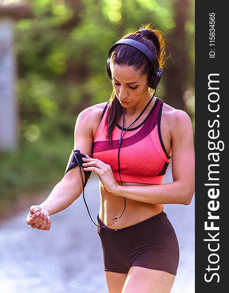 Young fitness woman listening music during workout in in the public park