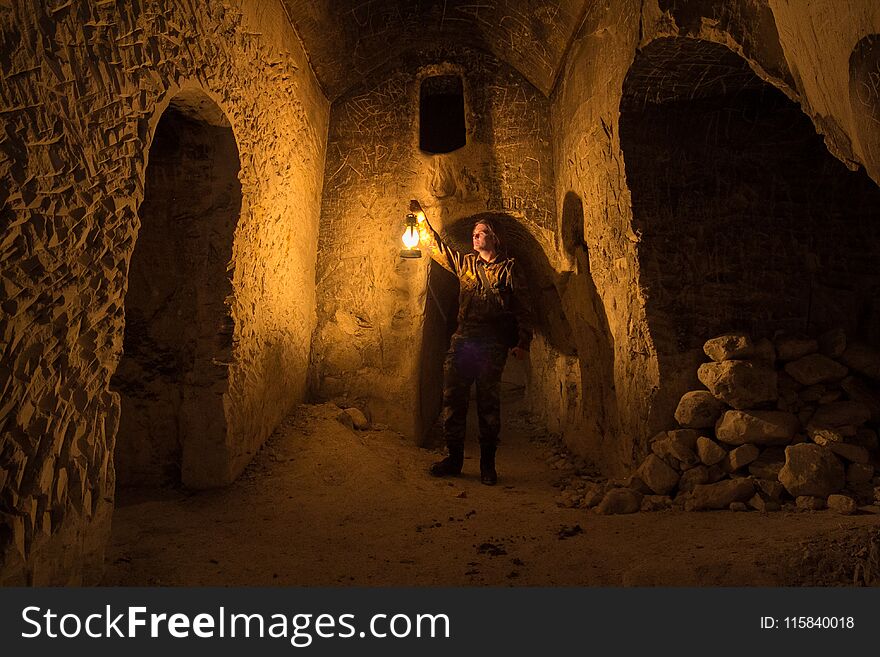 Man with kerosene lamp explores ancient abandoned underground chalky cave temple