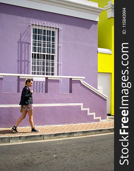 Woman Walking Near Purple Painted Building
