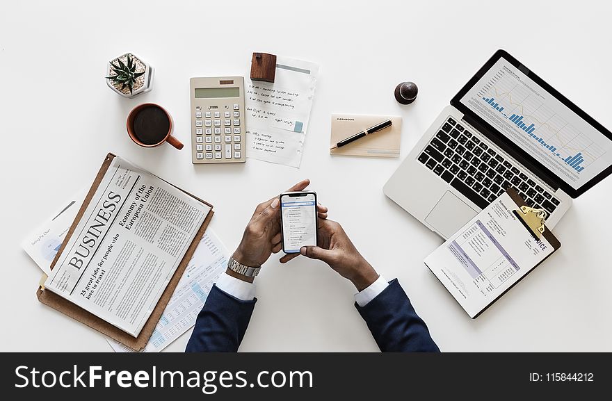 Top View of Man Holding Android Smartphone Near Macbook and Newspaper