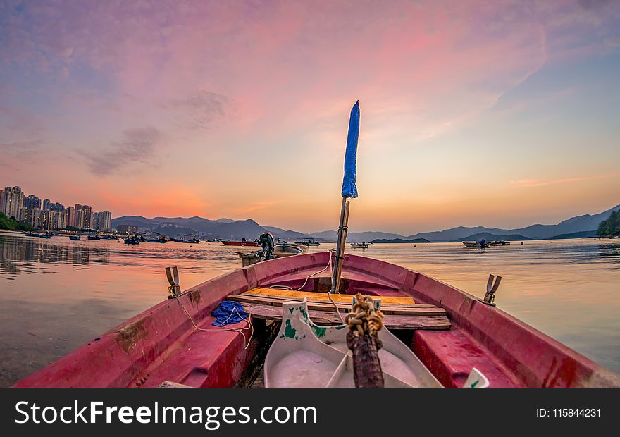 Red Boat on Body of Water With Blue Flag