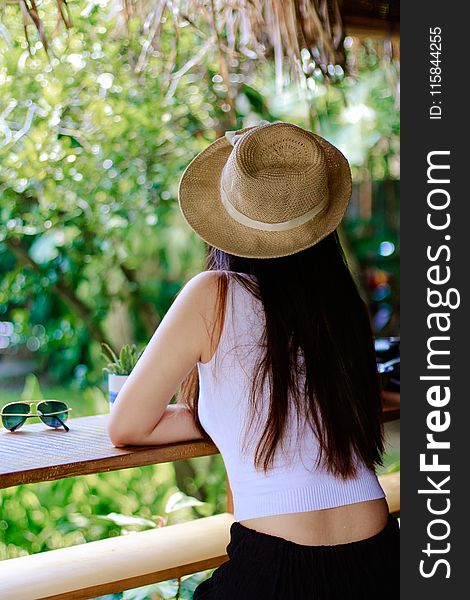 Woman Wearing White Tank Top And Black Pants With Brown Sun Hat