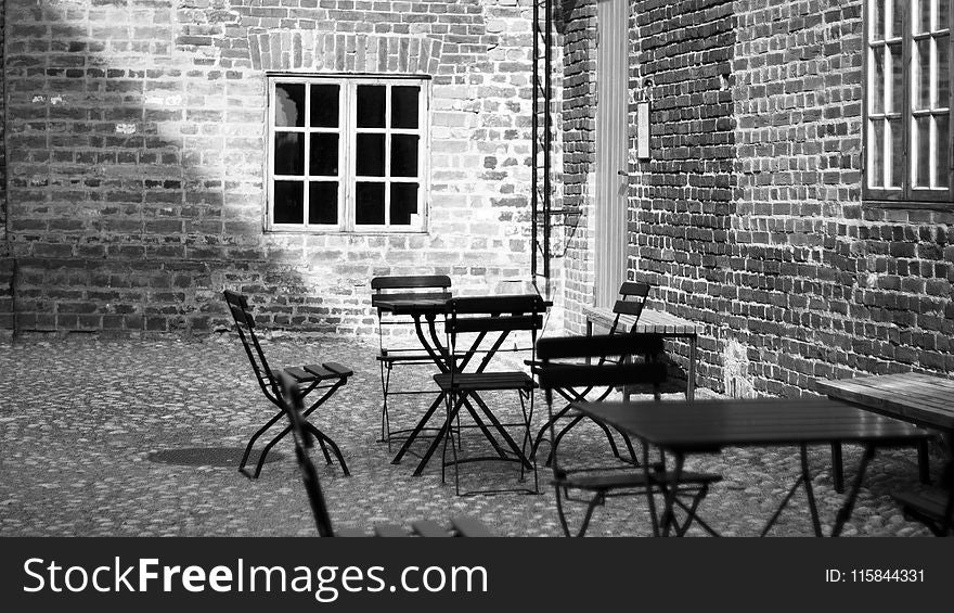 Grayscale Photo Of 4-piece Dining Set Near Concrete Building