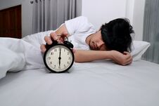 Young Asian Man Turn Off Alarm Clock On The Bed In Morning. Royalty Free Stock Photo Young Asian Man Turn Off Alarm Clock On The Bed In Morning. Royalty Free Stock Photo