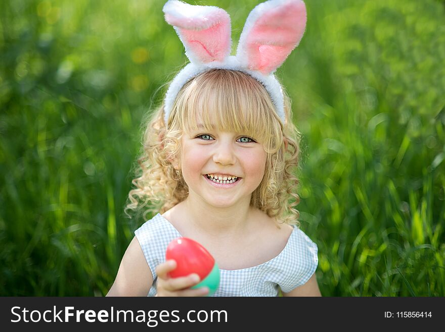 Cute funny girl with Easter eggs and bunny ears at garden. easter concept. Laughing child at Easter egg hunt