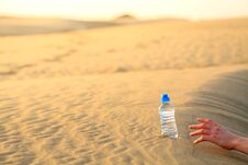 Hand Try To Catch The Bottle Of Water On Sand Deser Stock Images