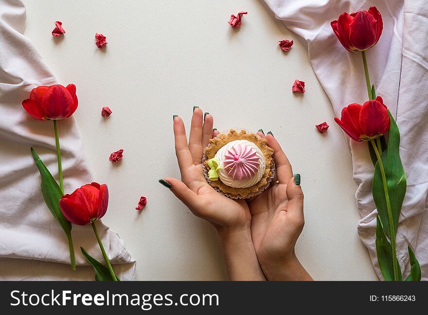 Cupcake in hand and flowers on white background