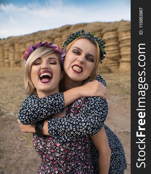 Couple of young lesbian girls laught in light dresses flirt, play laught and pet in the pasture in hayloft in