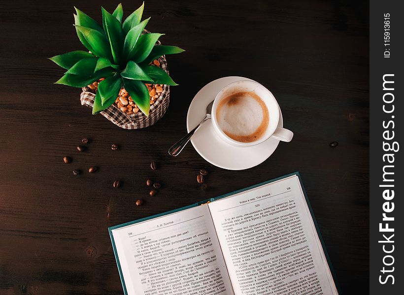 White Ceramic Mug On Saucer Near Book