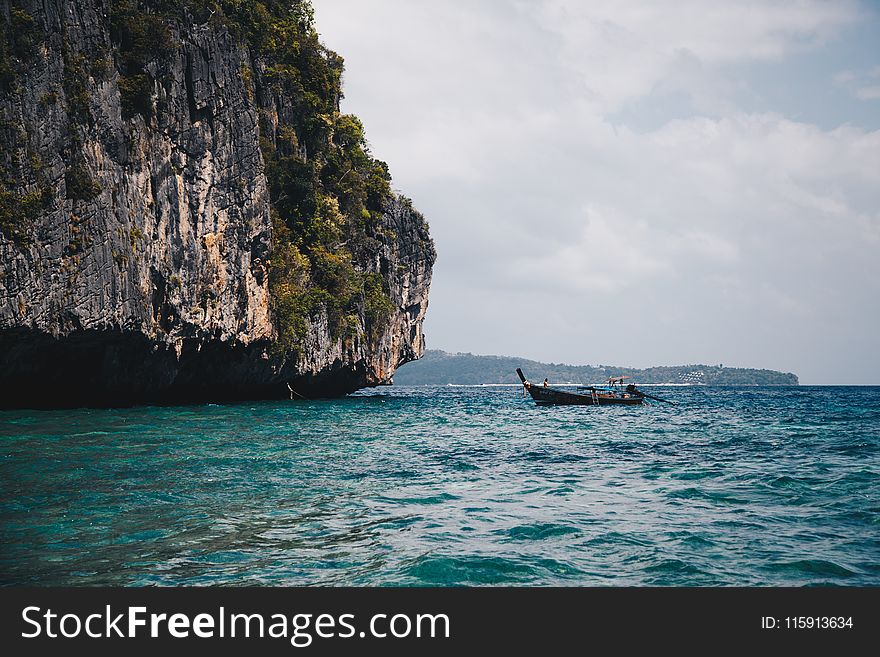 Boat Beside Cave on Body of Water