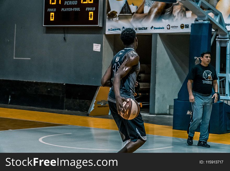 Man Holding Basketball on Blue Floor