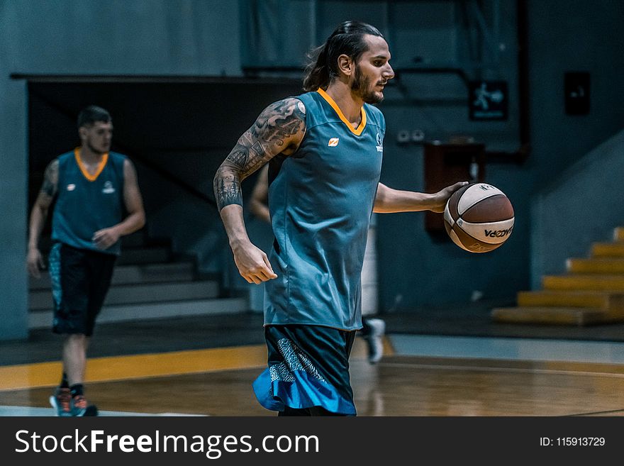 Man Holding Brown and White Basketball