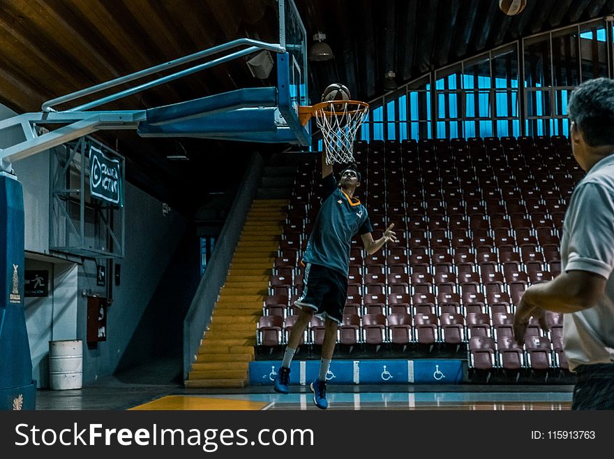 Man In Blue Shirt Trying To Dunk In Basketball Ring