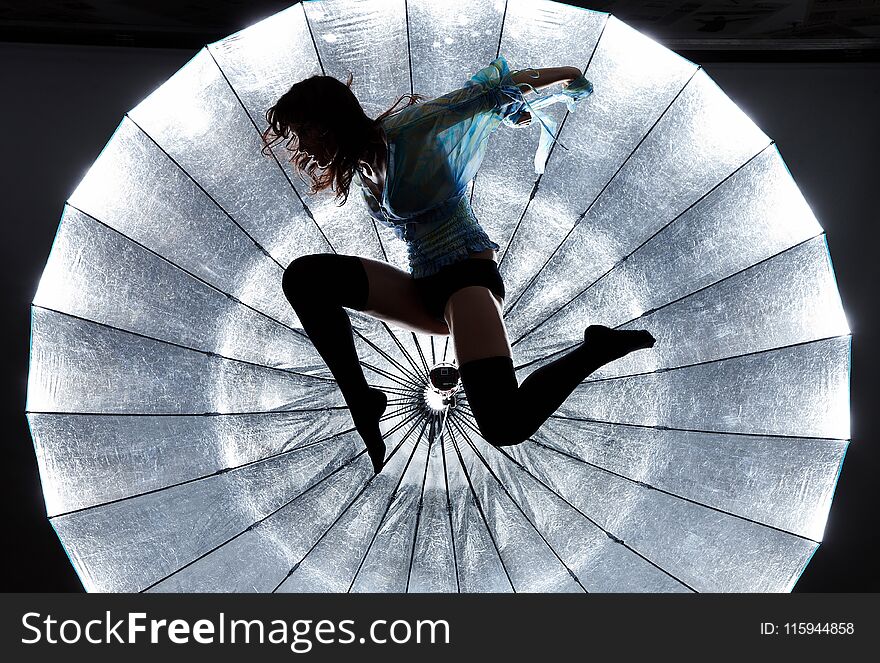 Jumping woman`s silhouette over bright background.