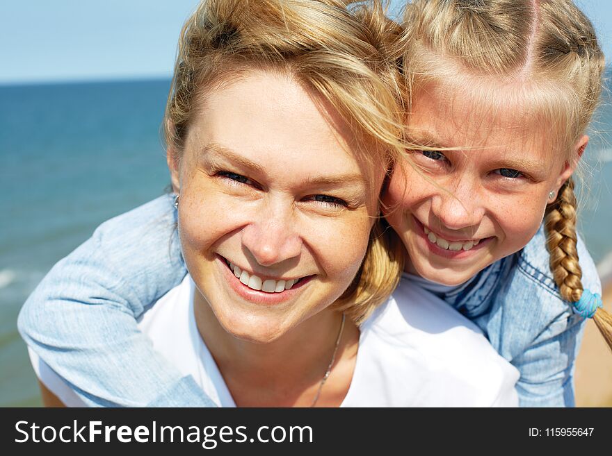 Happy mother and daughter laughing together outdoors. Close up