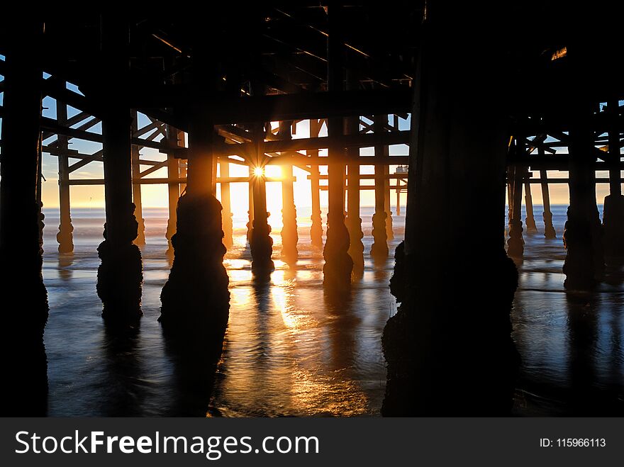 Dark silhouettes of the multitude of structural members an supports of this beach marine structure. Dark silhouettes of the multitude of structural members an supports of this beach marine structure.