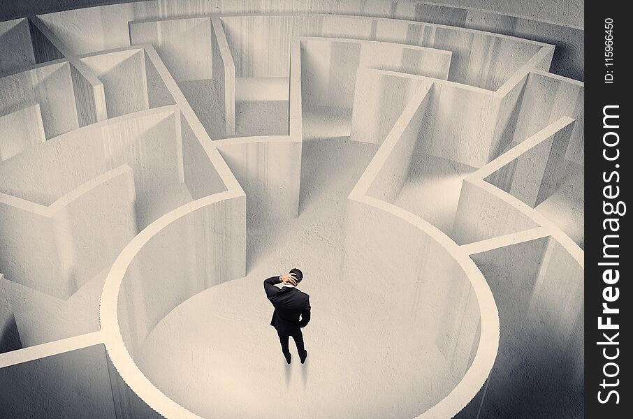 A confused businessman standing in the center of a maze surrounded with walls of the labyrinth. A confused businessman standing in the center of a maze surrounded with walls of the labyrinth
