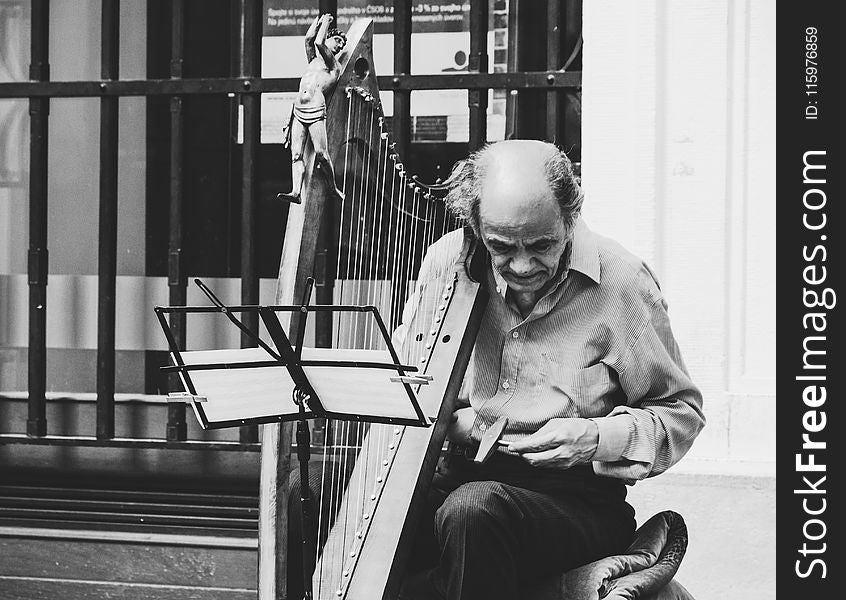 Greyscale Photo of Man Holding Harp