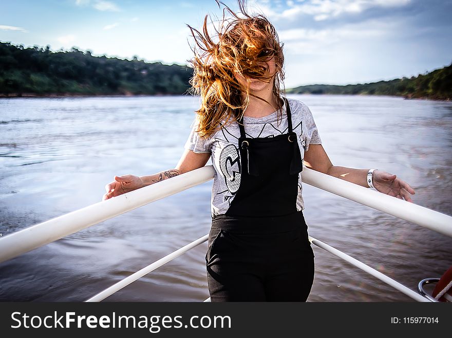 Woman Wearing Gray Shirt And Black Overalls On Boat