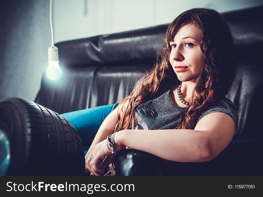 Woman in Gray Shirt Lying on Black Seat Sofa With Bulb Beside