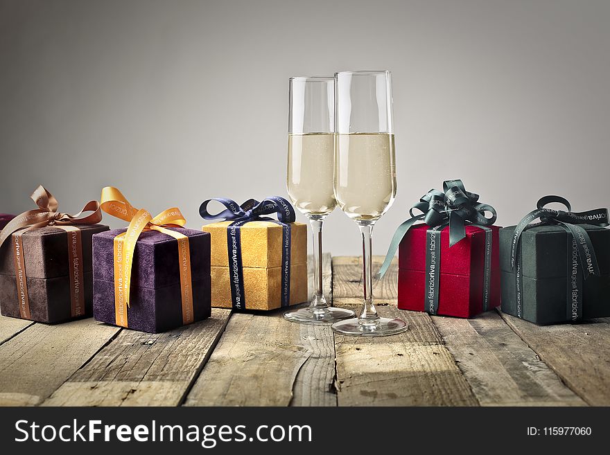 Five Assorted-color Gift Boxes and Two Footed Glasses on Top of Table