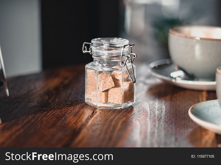 Clear Condiment Shaker With Brown Sugar Cubes Near Gray Teacup