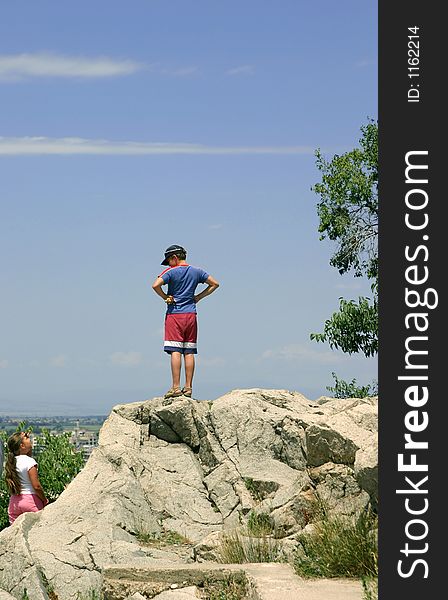 The teenager stands on a mountain, girl below