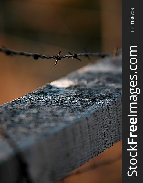 Closeup of barbed wire fence and old gray wooden railing