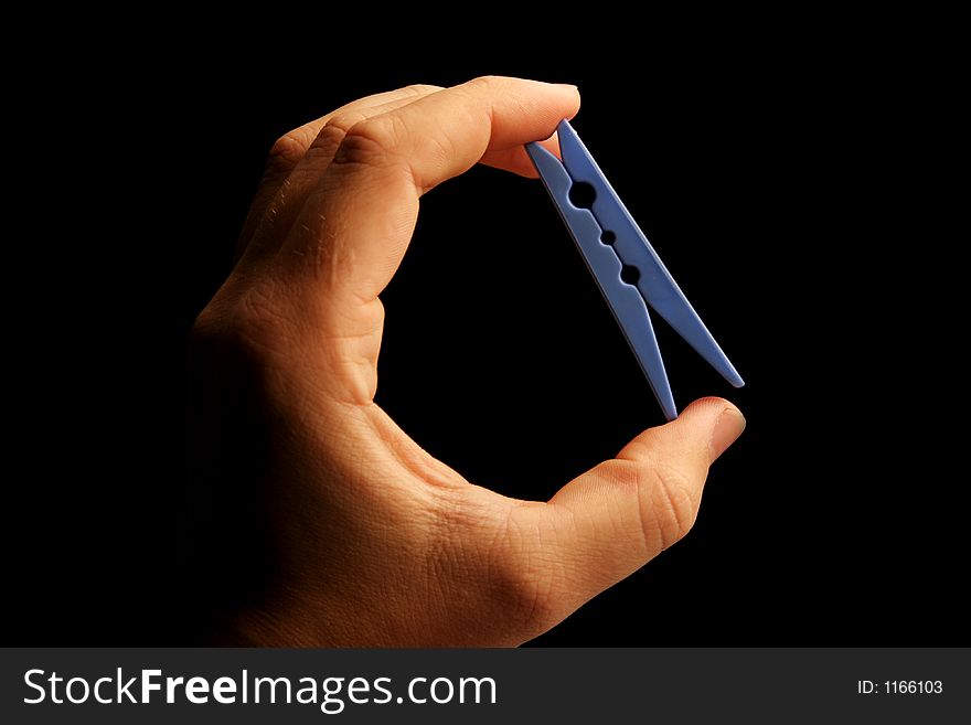 Hand holding clothes peg on black baackground. Hand holding clothes peg on black baackground