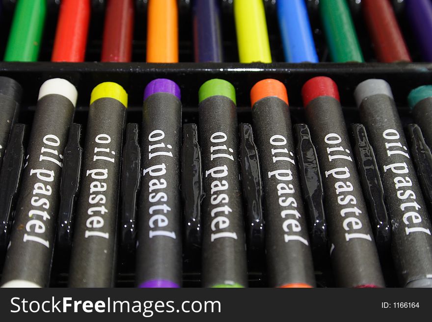 Colorful oil pastels in a black plastic tray case